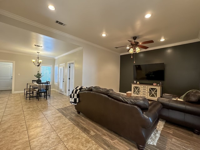 tiled living room featuring ceiling fan with notable chandelier and crown molding