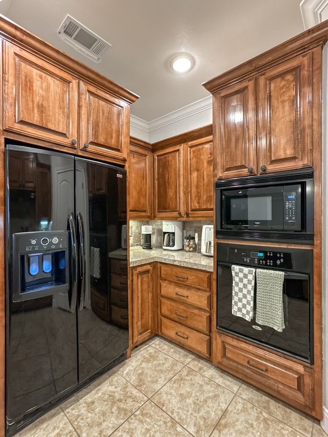 kitchen with crown molding, light tile patterned floors, black appliances, and light stone counters