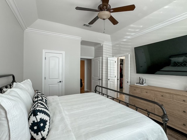 bedroom with ceiling fan, crown molding, hardwood / wood-style floors, a tray ceiling, and a closet