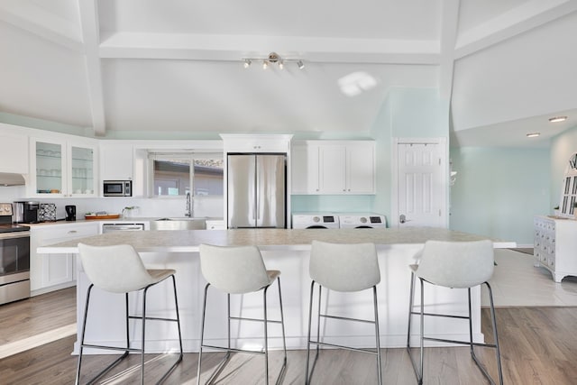 kitchen featuring a breakfast bar, beamed ceiling, white cabinets, and stainless steel appliances