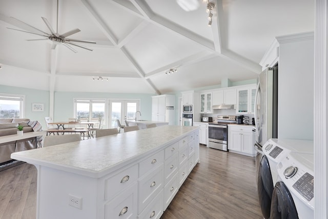 kitchen featuring washer and clothes dryer, a kitchen island, stainless steel appliances, and wood finished floors