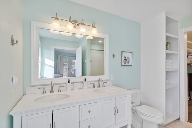 full bath with double vanity, toilet, and a sink