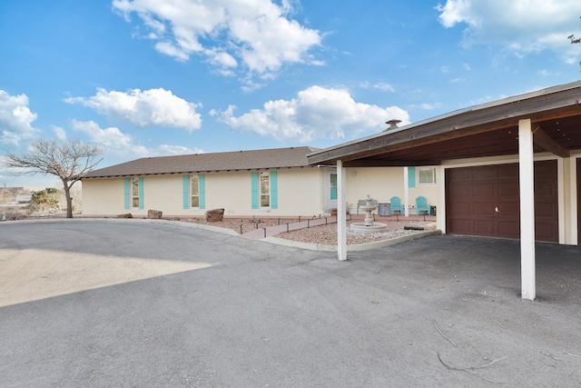 view of front of property featuring a garage, aphalt driveway, and stucco siding