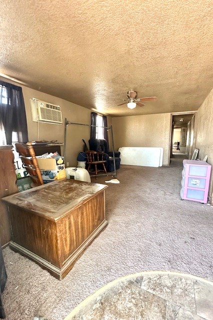 interior space with ceiling fan, a wall mounted air conditioner, carpet, and a textured ceiling