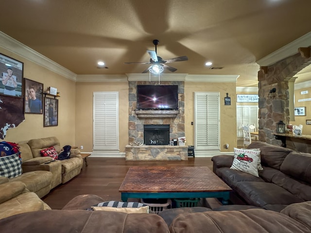 living room with crown molding, dark hardwood / wood-style floors, ceiling fan, and a fireplace