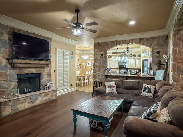 living room featuring a stone fireplace, crown molding, wood-type flooring, a textured ceiling, and ceiling fan