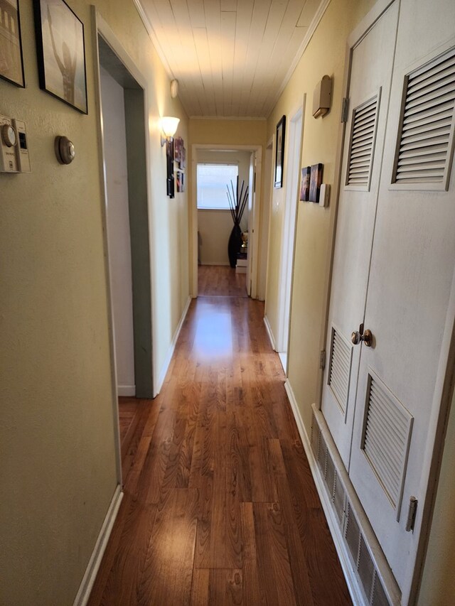 corridor with ornamental molding and dark wood-type flooring