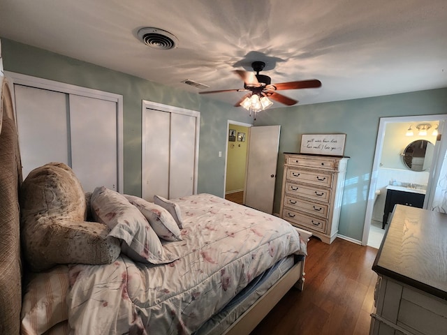 bedroom featuring multiple closets, connected bathroom, ceiling fan, and dark wood-type flooring