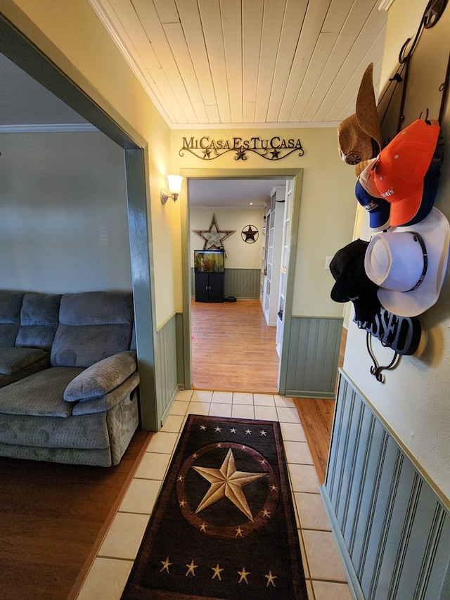 hall featuring tile patterned floors, ornamental molding, and wooden ceiling