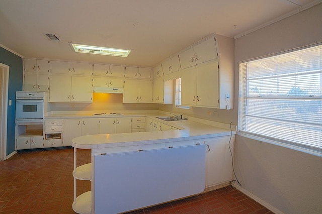 kitchen featuring kitchen peninsula, white cabinetry, sink, and white appliances