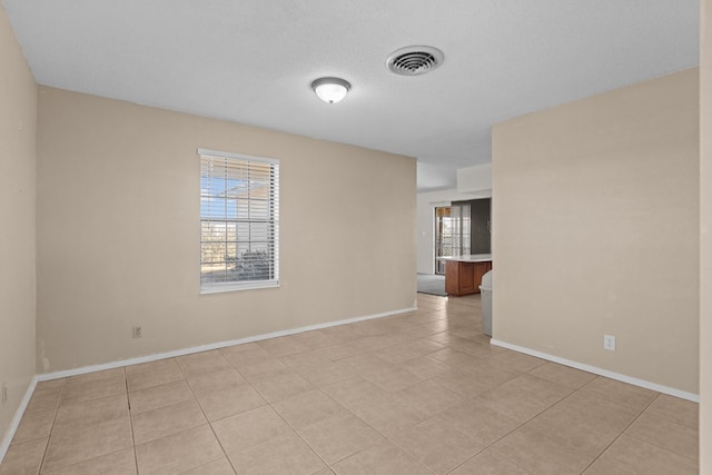 empty room with light tile patterned floors and a textured ceiling