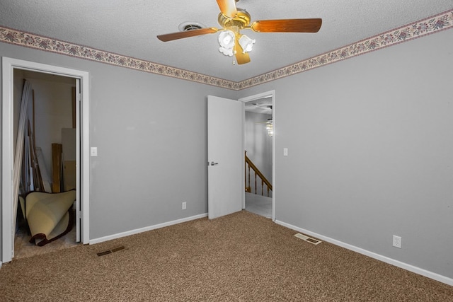 empty room featuring ceiling fan, carpet floors, and a textured ceiling