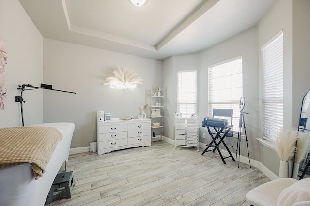 bedroom with baseboards, a raised ceiling, and wood finished floors