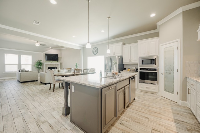 kitchen with decorative backsplash, stainless steel appliances, crown molding, a fireplace, and a sink