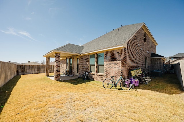 back of property with a patio area, brick siding, a lawn, and a fenced backyard