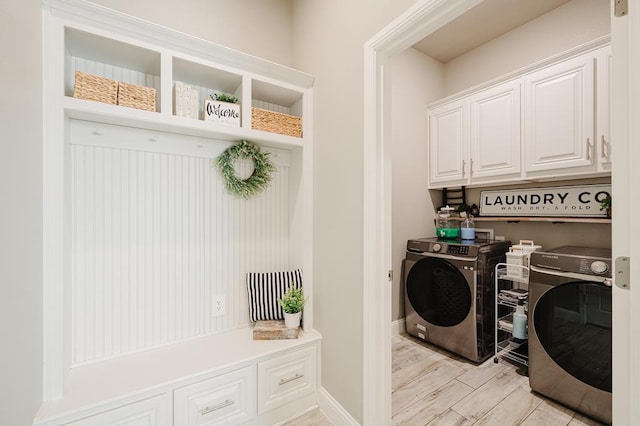 laundry room featuring cabinet space, washer and clothes dryer, baseboards, and light wood finished floors