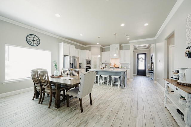 dining area featuring light wood-style floors, baseboards, and crown molding