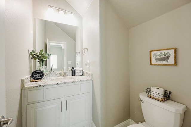 bathroom featuring toilet, vaulted ceiling, and vanity