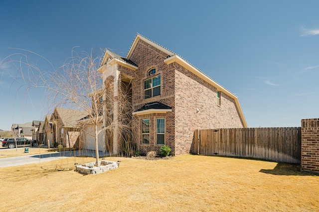 view of side of home with brick siding, fence, and driveway