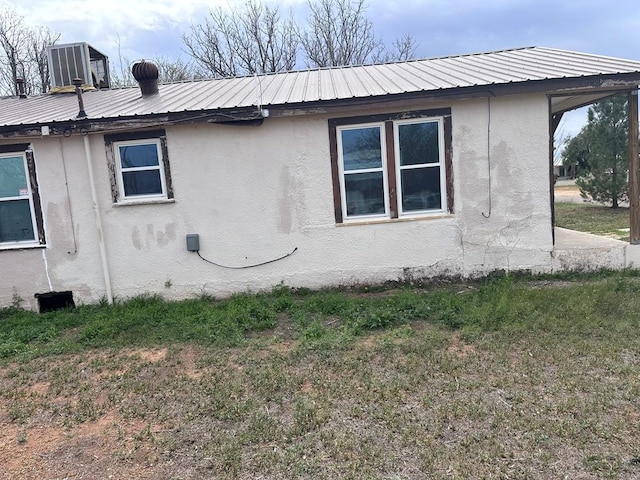 view of side of property featuring a yard and central AC