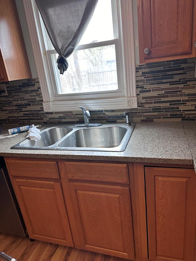 kitchen featuring dishwashing machine, tasteful backsplash, hardwood / wood-style flooring, and sink