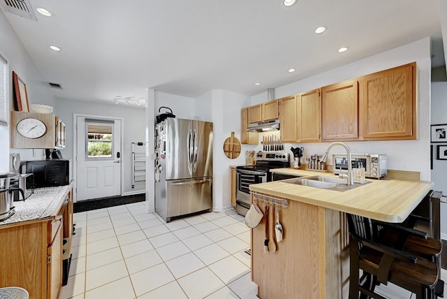 kitchen featuring a breakfast bar, sink, light tile patterned floors, kitchen peninsula, and stainless steel appliances