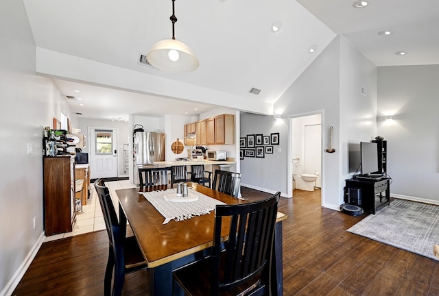 dining area with hardwood / wood-style flooring and high vaulted ceiling