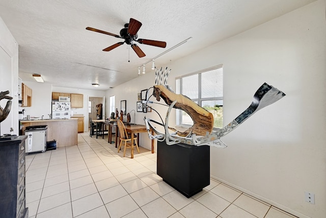 interior space with ceiling fan, light tile patterned flooring, and a textured ceiling