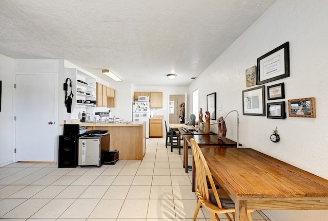 kitchen featuring white refrigerator, light tile patterned floors, a textured ceiling, light brown cabinetry, and kitchen peninsula