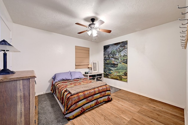 bedroom with ceiling fan, wood-type flooring, and a textured ceiling