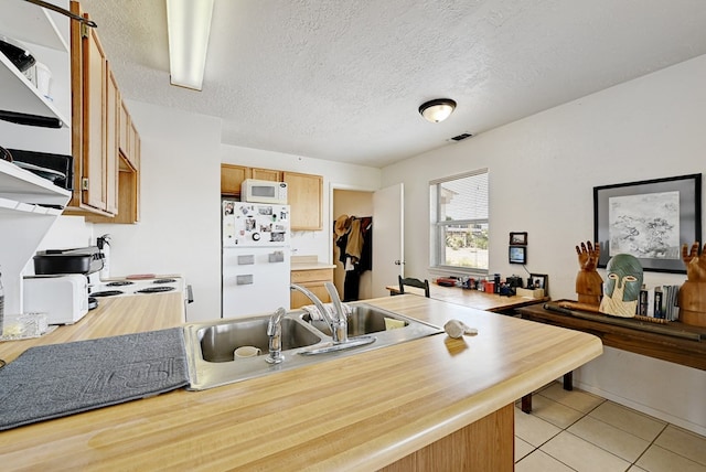 kitchen featuring a textured ceiling, white appliances, light tile patterned floors, and sink