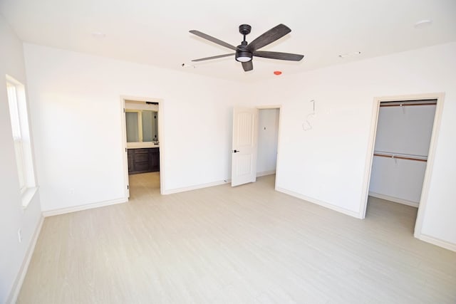 unfurnished bedroom with ceiling fan, a spacious closet, connected bathroom, light hardwood / wood-style floors, and a closet