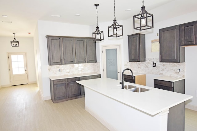 kitchen with dark brown cabinetry, a center island with sink, light hardwood / wood-style flooring, and sink