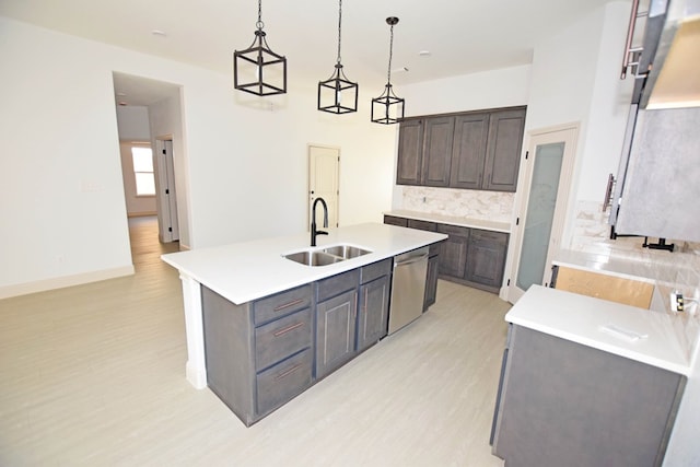 kitchen with stainless steel dishwasher, dark brown cabinetry, a kitchen island with sink, sink, and pendant lighting