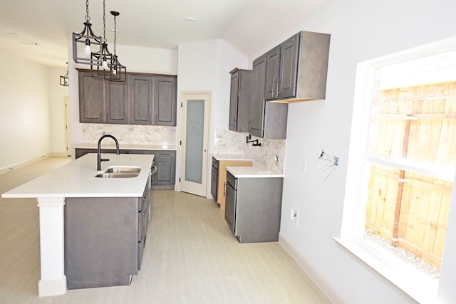 kitchen with decorative backsplash, dark brown cabinets, a center island with sink, and sink