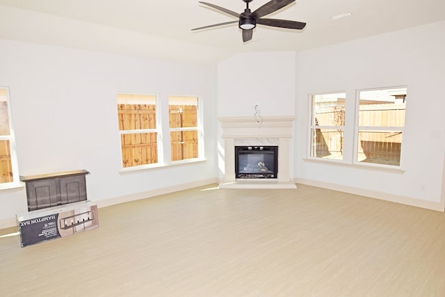 unfurnished living room with ceiling fan, a fireplace, vaulted ceiling, and light wood-type flooring