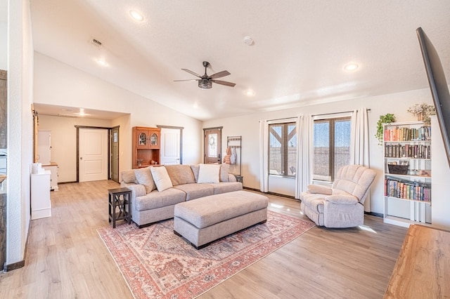 living room featuring ceiling fan, lofted ceiling, light hardwood / wood-style floors, and a textured ceiling