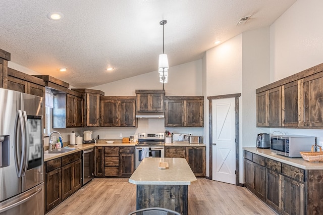 kitchen with sink, a center island, vaulted ceiling, pendant lighting, and stainless steel appliances