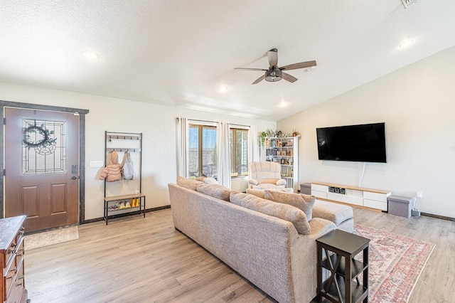 living room with ceiling fan, lofted ceiling, light hardwood / wood-style flooring, and a textured ceiling