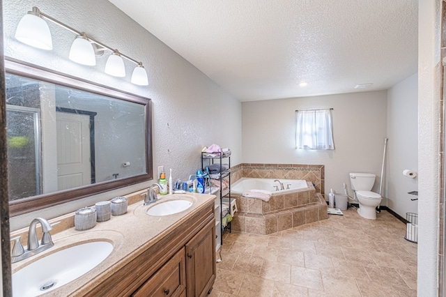 bathroom featuring vanity, a relaxing tiled tub, a textured ceiling, and toilet