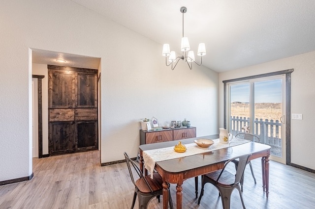 dining room featuring a notable chandelier, vaulted ceiling, and light wood-type flooring