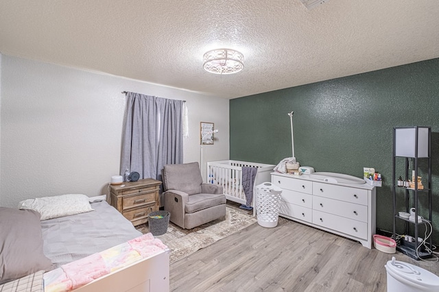 bedroom featuring light hardwood / wood-style floors and a textured ceiling