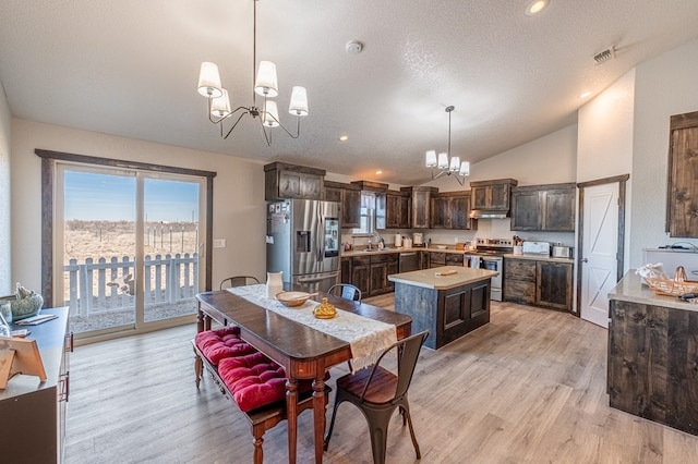 dining room featuring an inviting chandelier, vaulted ceiling, sink, and light wood-type flooring