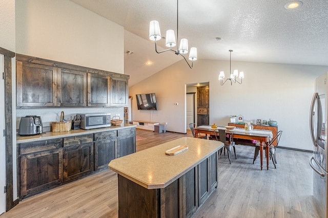 kitchen with a kitchen island, decorative light fixtures, a notable chandelier, stainless steel appliances, and dark brown cabinets