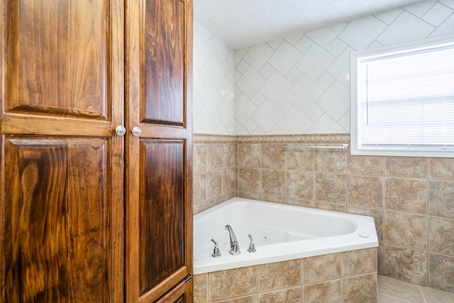 bathroom with tile walls, a tub with jets, and a textured ceiling