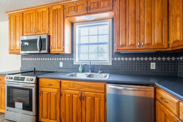 kitchen with a sink, dark countertops, brown cabinetry, and stainless steel appliances