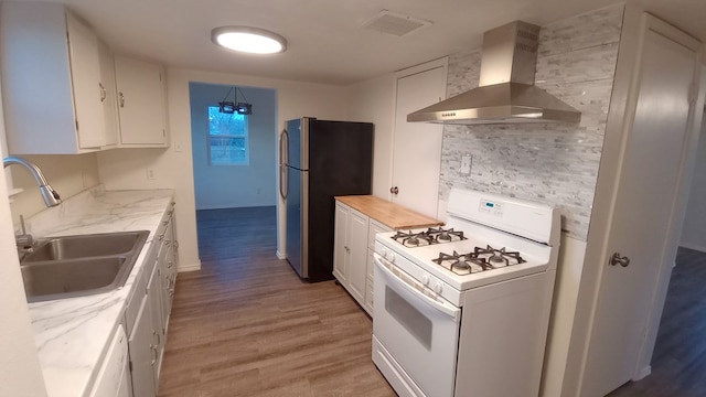 kitchen with sink, wall chimney exhaust hood, hardwood / wood-style floors, white appliances, and white cabinets