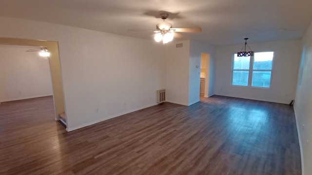 unfurnished living room with ceiling fan with notable chandelier and dark wood-type flooring