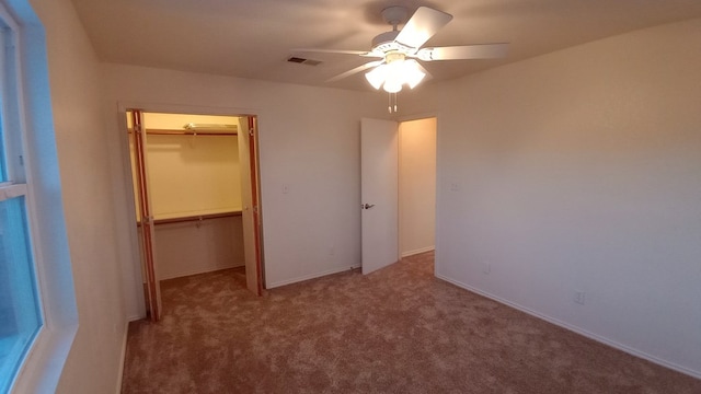 unfurnished bedroom with a walk in closet, carpet floors, a closet, and ceiling fan