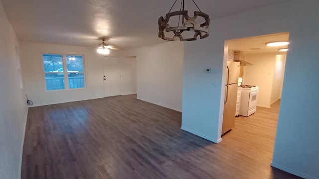 unfurnished living room with wood-type flooring and ceiling fan with notable chandelier